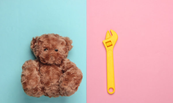 Teddy bear and toy wrench on a blue pink pastel background. Repair concept. Top view