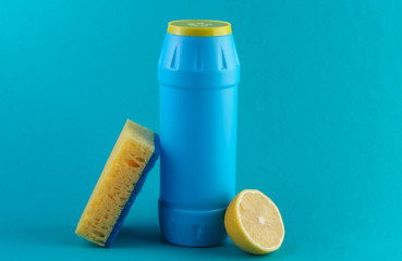 Bottle of detergent and lemon, sponge on a blue background.