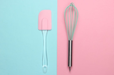 Kitchen spatula and whisk on pink blue pastel background. Minimalism. Top view