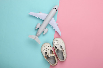flat lay composition of children's sandals and a toy airplane on a blue-pink pastel background. Top view