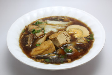 Chinese roll noodle soup (Guay Jub Nam Kon call in Thai) with crunchy pork, egg and cinnamon in white bowl on white background, it’s one of the top Thai street food dishes to try