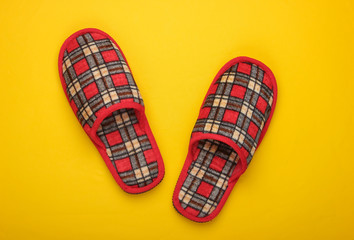 Checkered indoor slippers on a yellow background. Top view