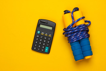 Fitness, sport concept. Calorie Counting. Calculator, jump rope on a yellow background. Top view