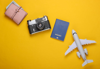 Flat lay travel composition on yellow background. Plane figurine, passport, wallet with dollars, camera. Recreation, vacation and tourism, minimalism concept. Top view