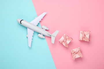 Air delivery. Plane figurine and gift boxes on pink blue pastel background. Flat lay. Top view