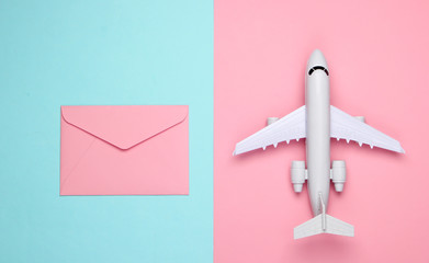 Air mail, air delivery. Flat lay composition with airplane figure and envelopes of letters on pink blue pastel background. Top view