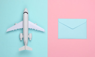 Air mail, air delivery. Flat lay composition with airplane figure and envelopes of letters on pink blue pastel background. Top view