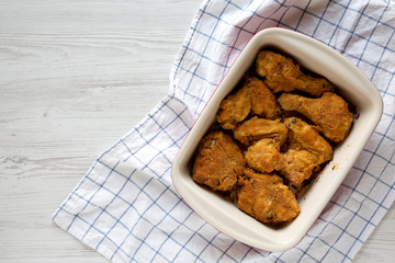 Crispy homemade oven baked fried chicken in a dish on a white wooden background, top view. Flat lay, overhead, from above. Copy space.
