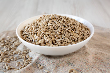 Raw Sunflower Seed Kernels in a white bowl on a white wooden surface, low angle view.