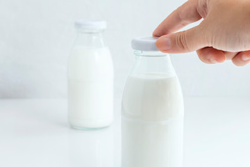 Woman hand's holding a cap of glass bottle milk isolated on white table background for food and healthy concept. with copy space for text.