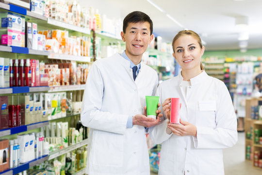 Portrait of two pharmacists posing with medicine in apothecary