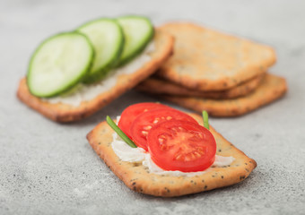 Various healthy crackers with cream and tomato with cucumber on light kitchen table background. Macro