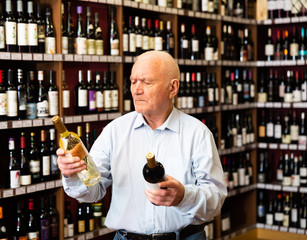 Serious retiree chooses white and red wine in a liquor store