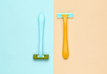 Minimalistic beauty concept. Two plastic razor on blue yellow pastel background. Top view