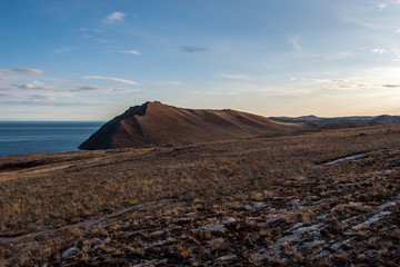 View of the shore of Lake Baikal. Brown rocks in the shade. Evening, sunset.