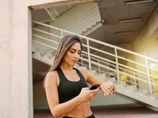Attractive sport woman in sportswear use smart watch outdoors at urban environment