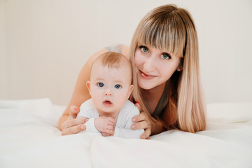 portrait. mom and baby lie on bed, look at camera