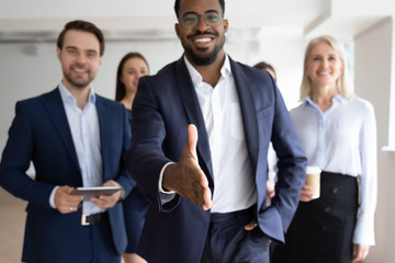 Group portrait of smiling multiracial businesspeople greeting newcomer to successful team, happy...