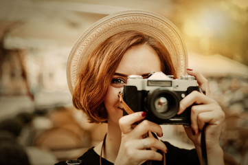 Smilling hipster woman holding a retro camera in her hands and taking a picture