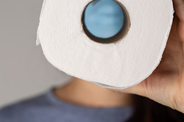 A woman is wearing a face mask for protection from the Corona Virus and has stocked up on her toilet paper stash in case of quarantine.