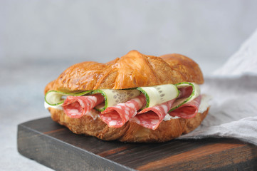 Croissant stuffed with salami, fresh cucumber and cottage cheese. Croissant occupies the entire frame space. Macro shot.