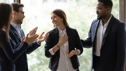 Diverse multiethnic businesspeople applaud greeting with promotion young female colleague at meeting, multiracial coworkers clap hands thanking for presentation or business success to woman employee