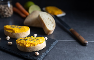 Homemade hummus chickpea spread made of chickpea, carrots, lemon and coriander. Spread over a toast, made of organic ingredients. Refreshing vegan breakfast.