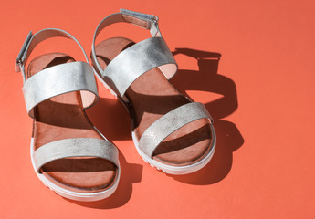 Stylish women's sandals on orange background. Summer footwear