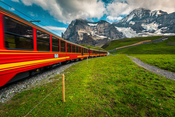 Fototapeta na wymiar Cogwheel tourist train and snowy Jungfrau mountains in background, Switzerland