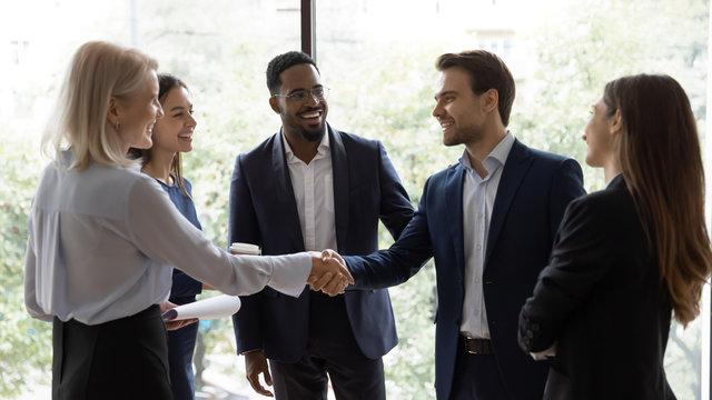 Smiling diverse businesspeople shake hands greeting getting acquainted at office meeting, happy colleagues employees handshake closing deal or making agreement after successful negotiations