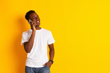 Young african guy talking by cell phone and smiling