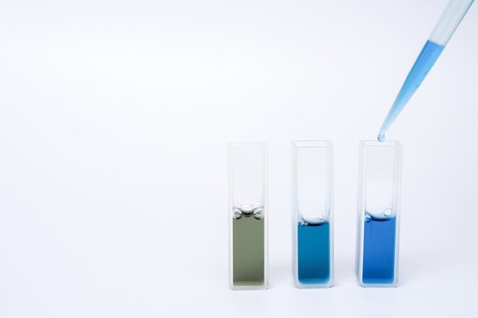 Adding blue reagent into the cuvette on isolated white background.