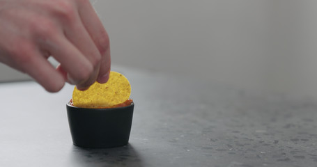 dip round corn chips in salsa closeup