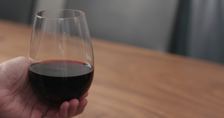 man hand take wineglass with red wine from walnut table with copy space
