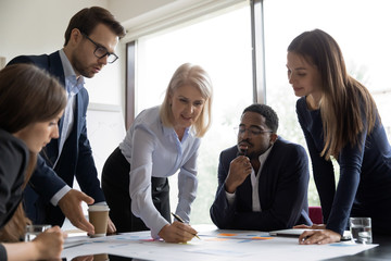 Concentrated multiracial colleagues brainstorm discussing business company ideas at briefing in...