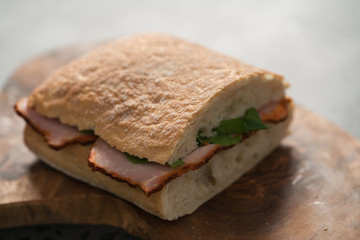 sandwich with smoked pork, spinach and pesto on olive wood board