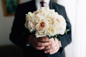 Obraz na płótnie Canvas Stylish groom holding beautiful wedding bouquet