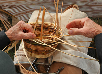 hands of an elderly man weave a wicker