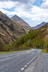Naklejka premium A scottish road in the Isle of Skye with a dramatic sky and mountains