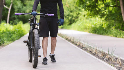 Naklejka premium Cropped image of cycler holding bike in public park