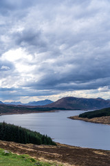 Beautiful layers of color of rural Isle of Skye landscape on an overcast day. From loch shore at low tide to the rolling hills of the countryside and the Cuillin mountain range