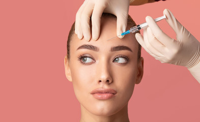 Young Woman Receiving Botox Beauty Injection In Forehead, Studio Shot