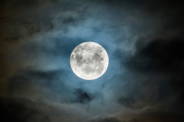 Fototapeta na wymiar A full moon lights up a blanket of clouds