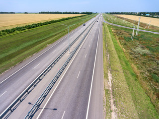 Wide highway with four lanes, aerial view at straight motorway in agricultural fields. Russia