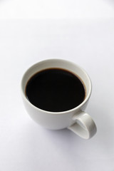 hot coffee cup on white table with soft-focus and over light in the background