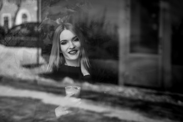 portrait of a beautiful young blonde woman with coffee. a girl sits in a cafe in the morning with coffee and looks out the window