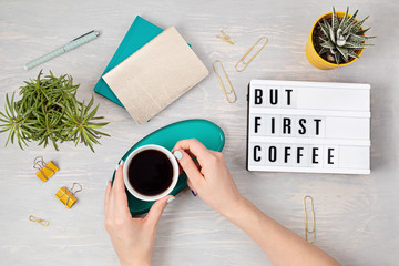 Flat lay with lightbox with text "But first coffee" and coffee cup in woman hand. Social media, feminine blog, morning of workday concept