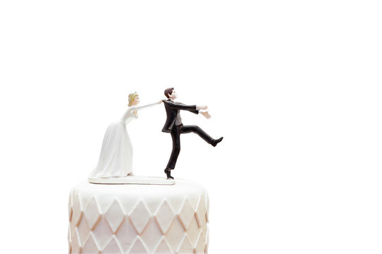 groom doll and statue is running away but bride can catch him finally. the funny wedding story doll on the top of cake with isolated object on white background and clipping path.