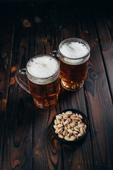 Appetizing salty beer snacks. Two mugs of craft lager and pistachios. Oktoberfest food, pub concept