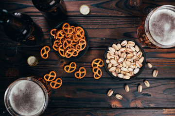 Appetizing salty beer snacks. Two mugs of craft lager, pretzels and pistachios. Oktoberfest food, pub concept